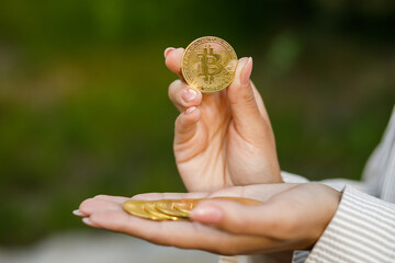 Closeup of hand holding golden bitcoin, copy space for cryptocurrency commercial, digital money, electronic investment. Cropped portrait of businesswoman holding bitcoin and showing it to the camera.