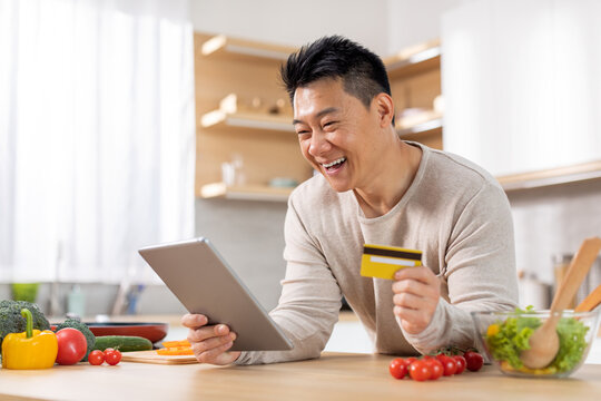Happy chinese man buying food online, cooking at home