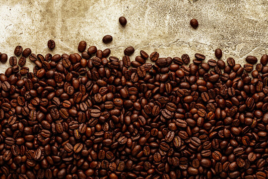 Brown organic roasted coffee beans on light rough background with stone texture