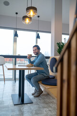 Man with coffee sitting sideways smiling at camera
