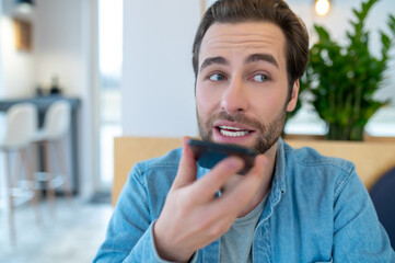Man looking away holding smartphone at mouth level