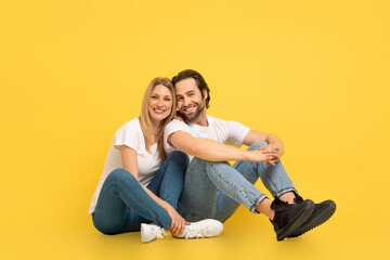 Relationship of people and ad. Cheerful millennial caucasian woman and man in white t-shirts are sitting on floor