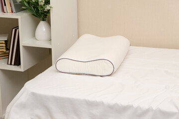 White orthopedic memory foam pillow on the bed. Comfortable pillow for healthy sleep.