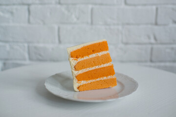 A piece of orange cake on a white plate