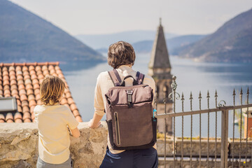 Dad and son tourists enjoying Colorful street in Old town of Perast on a sunny day, Montenegro. Travel to Montenegro concept. Scenic panorama view of the historic town of Perast at famous Bay of Kotor
