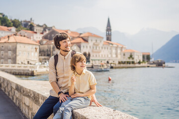 Fototapeta na wymiar Dad and son tourists enjoying Colorful street in Old town of Perast on a sunny day, Montenegro. Travel to Montenegro concept. Scenic panorama view of the historic town of Perast at famous Bay of Kotor