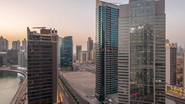 Cityscape of skyscrapers in Dubai Business Bay and downtown with water canal aerial day to night transition timelapse. Modern skyline with towers and waterfront after sunset. A center of international