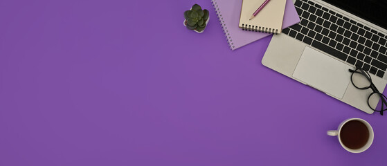 Top view flat lays of a laptop, note books, a cup of coffee on a purple background. For business and technology concept.