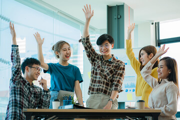 A group of creative young Asians in casual wear join hands to celebrate the success of their office project. Many men and women stood together at the beginning. teamwork concept of colleagues