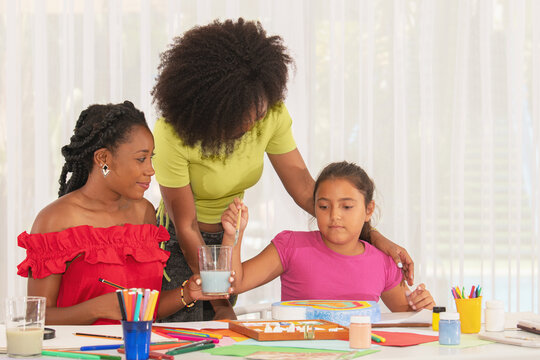Two teachers helping to student girl to painting in art class
