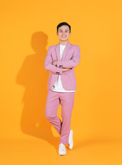 Full length image of young Asian man  standing on orange background