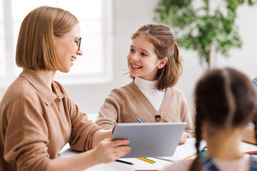 Woman with tablet teaching children at school