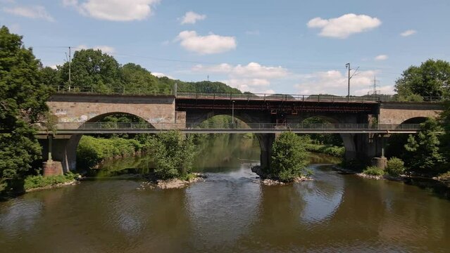 Aerial fly through shot of a stone train bridge within the lush nature of west Germany in spring.