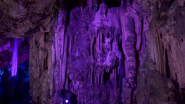 Massive stalactites in St. Michael's cave lit by purple light, Gibraltar.