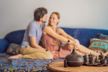 Couple resting at home. Aromatherapy Concept. Wooden Electric Ultrasonic Essential Oil Aroma Diffuser and Humidifier. Ultrasonic aroma diffuser for home