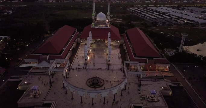 Circling drone shot of the great Mosque of Central Java (MAJT) in the night. The light is on. It have some pillars and some umbrela that is closed