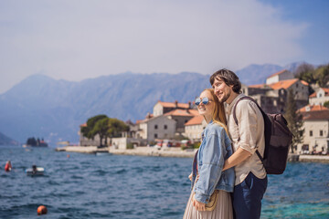 Fototapeta na wymiar Happy couple in love man and woman tourists enjoying Colorful street in Old town of Perast on a sunny day, Montenegro. Travel to Montenegro concept. Scenic panorama view of the historic town of Perast