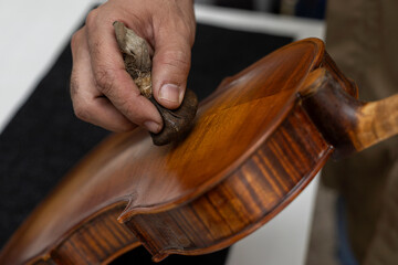 Close-up of unrecognizable Latin American Luthier varnishes a violin the old fashioned way using...