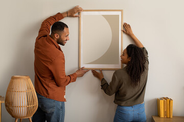 Black Husband And Wife Hanging Picture In Frame At Home