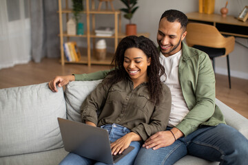 Happy African American Couple Using Laptop Computer At Home