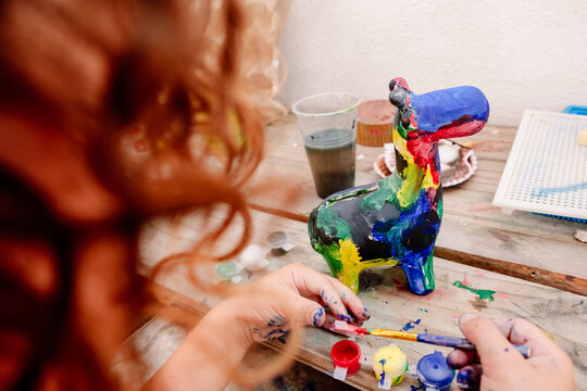 Child Plays To Unleash His Creativity By Decorating A White Plaster Figure With Colored Paints, During The Summer Holidays.
