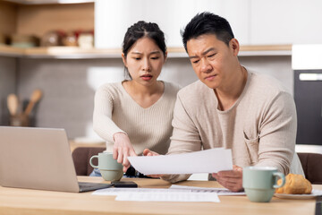 Upset japanese husband and wife checking their expenses