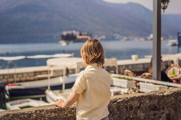 Fototapeta na wymiar Boy tourist enjoying Colorful street in Old town of Perast on a sunny day, Montenegro. Travel to Montenegro concept. Scenic panorama view of the historic town of Perast at famous Bay of Kotor on a
