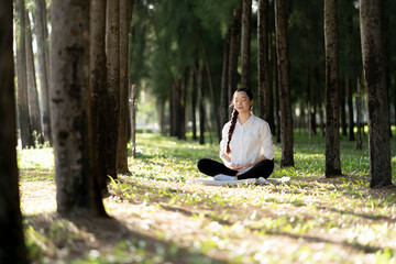 Attractive Healthy Asian Woman meditating in the park