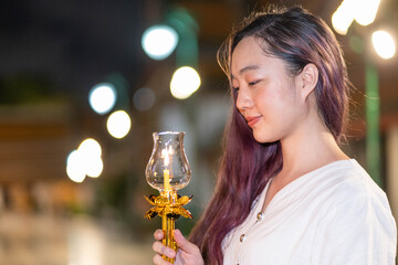 portrait young asian woman wearing traditional dress of Thailand holding candle for pray and meditation, Visakabucha day