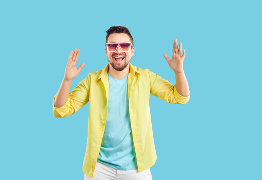 Overjoyed Young Man In Sunglasses Isolated On Blue Studio Background Feel Excited And Joyful. Smiling Funny Male Laugh Show Big Size Measurement With Hands. Great Sales Or Deals.