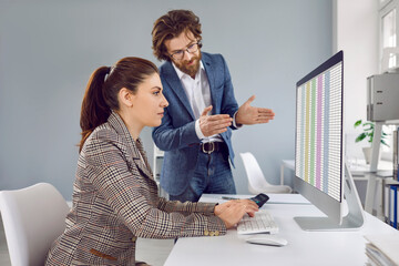 People working in office. Male manager talking to female trainee, giving advice and explaining...