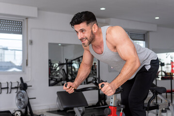 Plakat athlete man training in the gym with stationary bike doing spinning