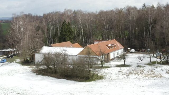 Farmhouse secluded in tree grove in early winter countryside, drone.