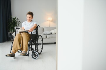 Shot of a senior woman sitting in a wheelchair and reading book at home