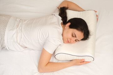 A woman sleeps on her stomach on an orthopedic pillow made of memory foam.
