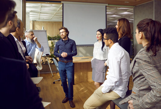 Business Planning. Variety Of Multiracial Smart Employees Communicate At Team Meeting In Modern Office. Man Shares Ideas During Brainstorming Session Discussing Business Project At Group Briefing.