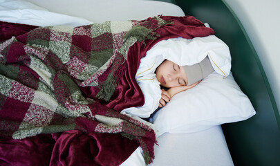 Teenager girl is feeling cold, covered with warm blanket, sleeping on bed at home, having problem...