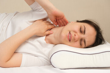 Fototapeta na wymiar A woman has a sore neck after sleeping on the wrong uncomfortable pillow