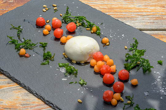 burrata cheese with melon salad and ruccola on crispy roasted pine nuts
