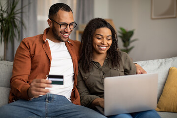 African Couple Shopping Online Via Laptop And Credit Card Indoor