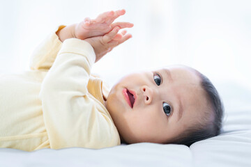 Asian baby girl with white skin and big eyes  naughty age  playing on the bed by the bedroom window