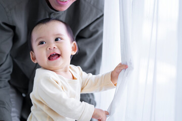 baby girl with asian father smiling baby happily playing together in bed in the bedroom at home