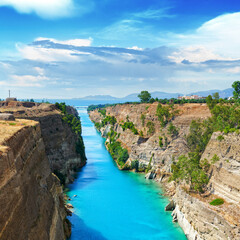 Scenic summer landscape of the Corinth Canal in a bright sunny day against a blue sky with white clouds. Peloponnese, Greece - obrazy, fototapety, plakaty