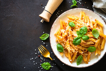 Italian pasta with tomato sauce, basil and parmesan cheese on dark table.