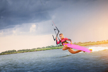 A young woman kitesurfer rides the waves doing a trick. Marine sports. kitesurfing