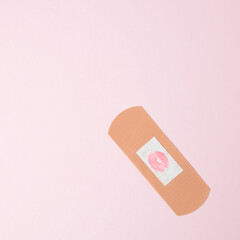 Love layout made with first aid plaster with kiss shaped stain on pink background. Minimal concept. Flat lay.