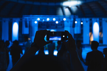 Unrecognizable man takes a photo with his phone at a music concert