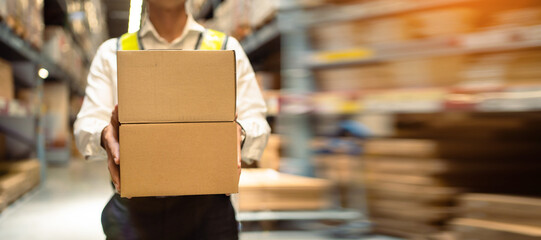 Close-up, workers carrying boxes in a large logistics warehouse. Concept of export-import logistics...