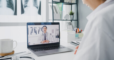 Young Asia lady doctor in white medical uniform using laptop talking video conference call with...