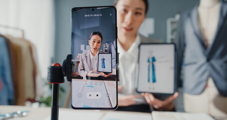 Professional cheerful Asia businesswoman designer sitting on table  look at smartphone online...